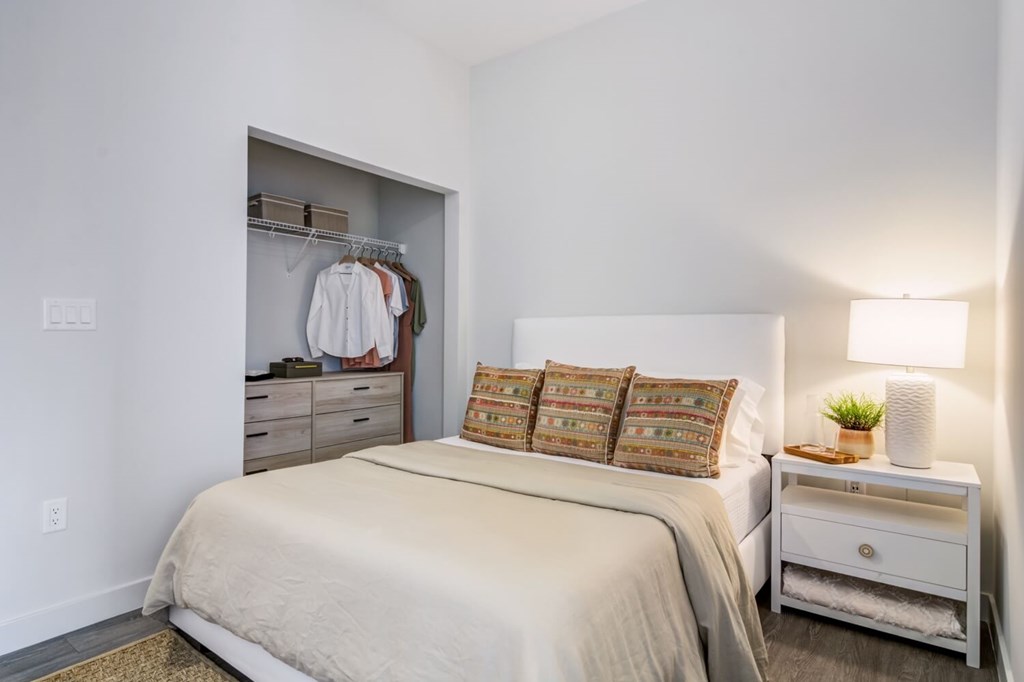 A bedroom with a bed, nightstand, and closet.