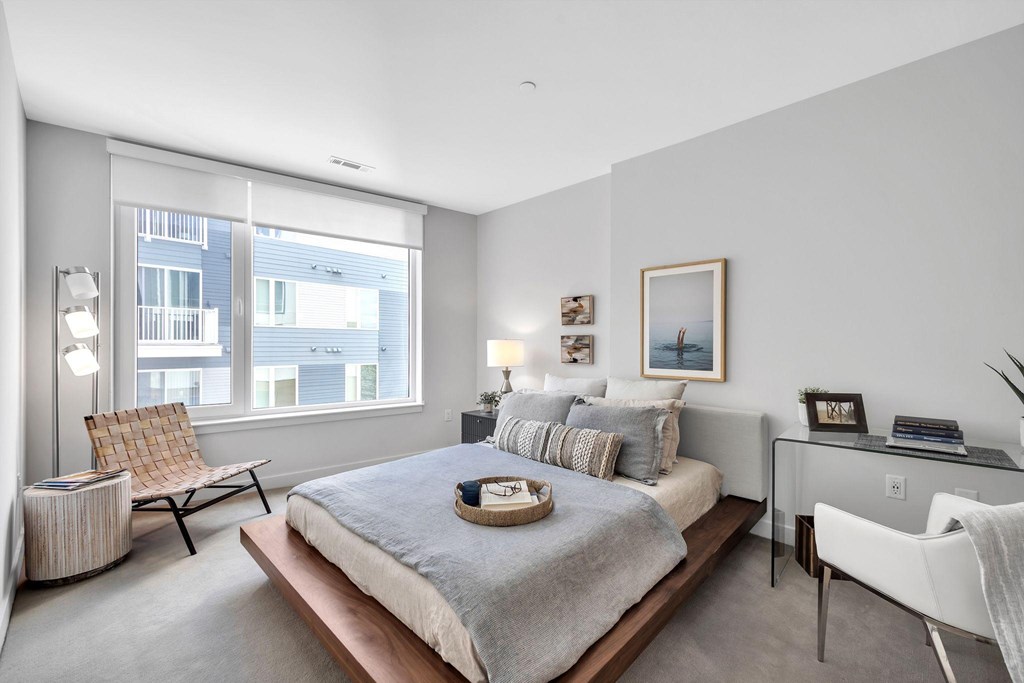 A bedroom with a large bed, a chair, and a desk.