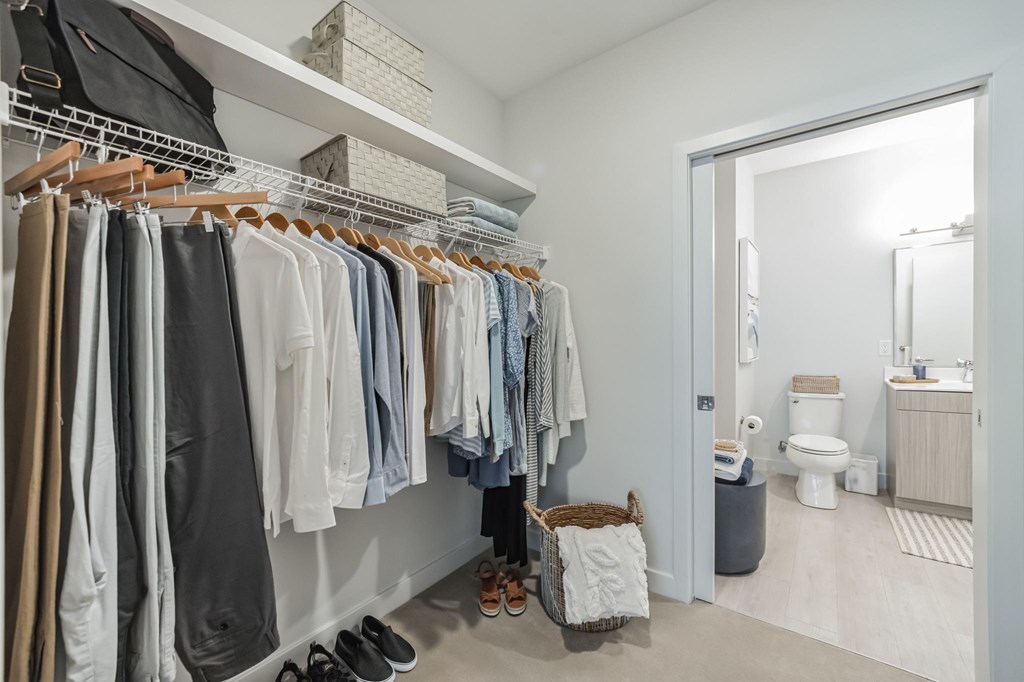A white closet with clothes and shoes.