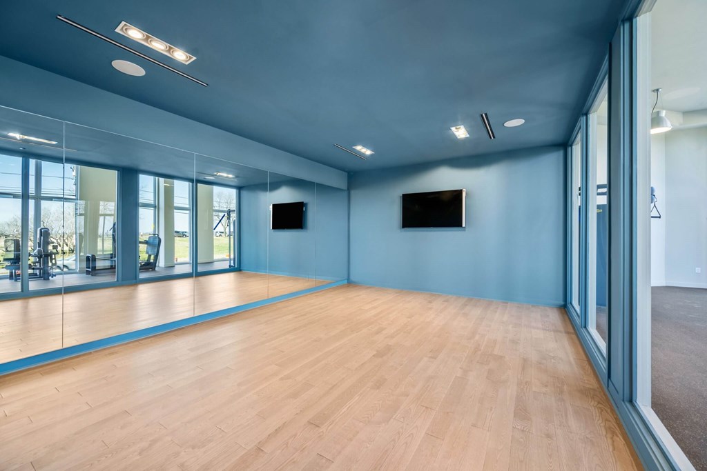 A spacious room with wooden floors and a television mounted on the wall.