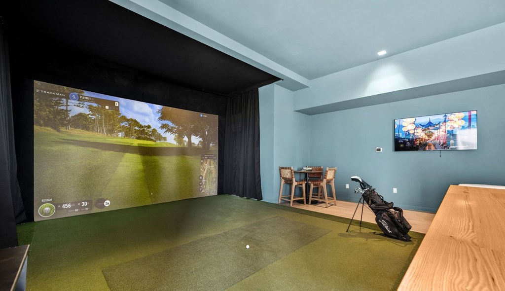 A golf simulator room with a screen showing a golf course.