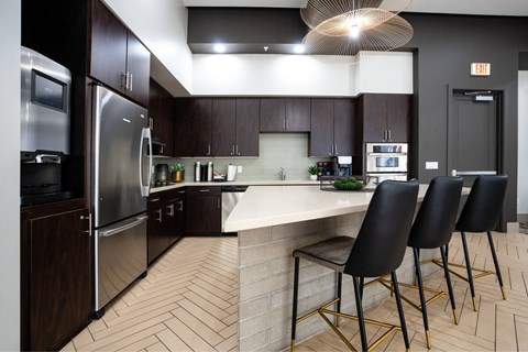 A kitchen with a white counter top and black chairs.