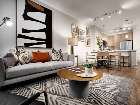 A modern living room with a grey couch, a coffee table, and a large abstract painting on the wall.