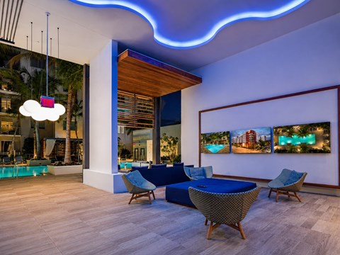 A modern living room with a blue sofa and a large window overlooking a pool.