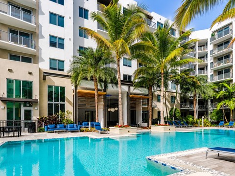A large swimming pool in front of a building with palm trees.