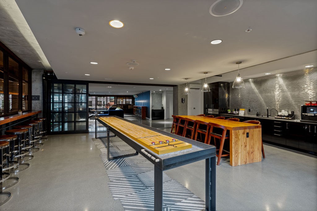 A modern kitchen with a long wooden table and bar stools.
