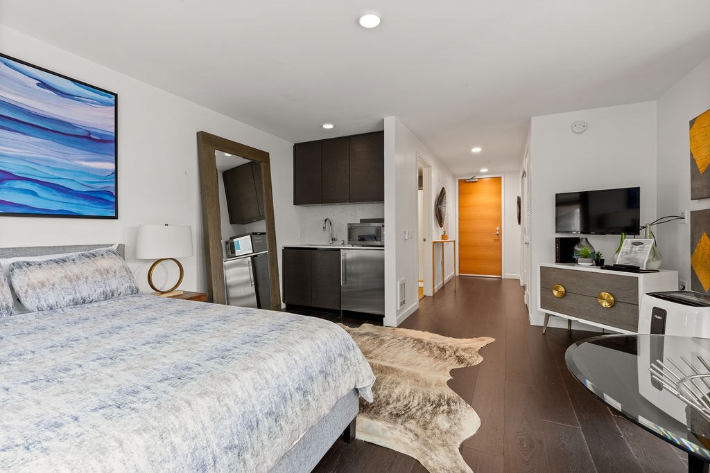 A bedroom with a large bed and a painting on the wall.