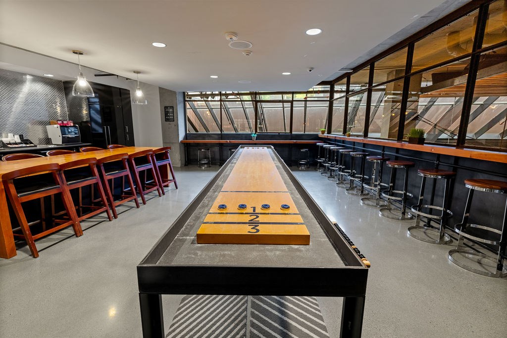 A shiny wooden table with numbered slots is in the middle of a room with a bar.