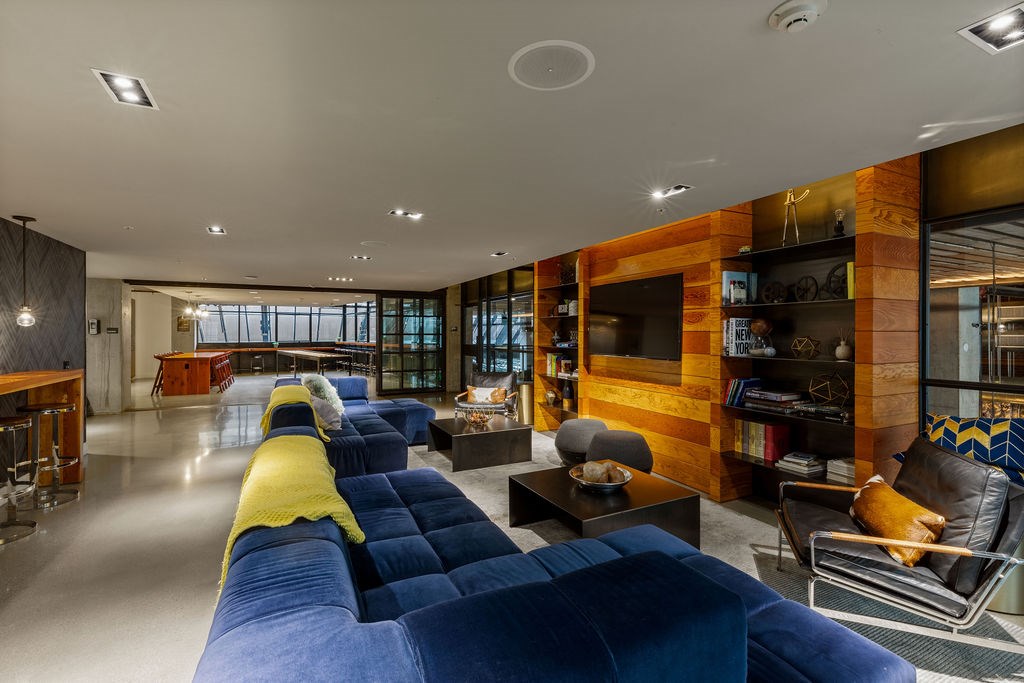 A modern living room with a long blue couch and a wooden accent wall.