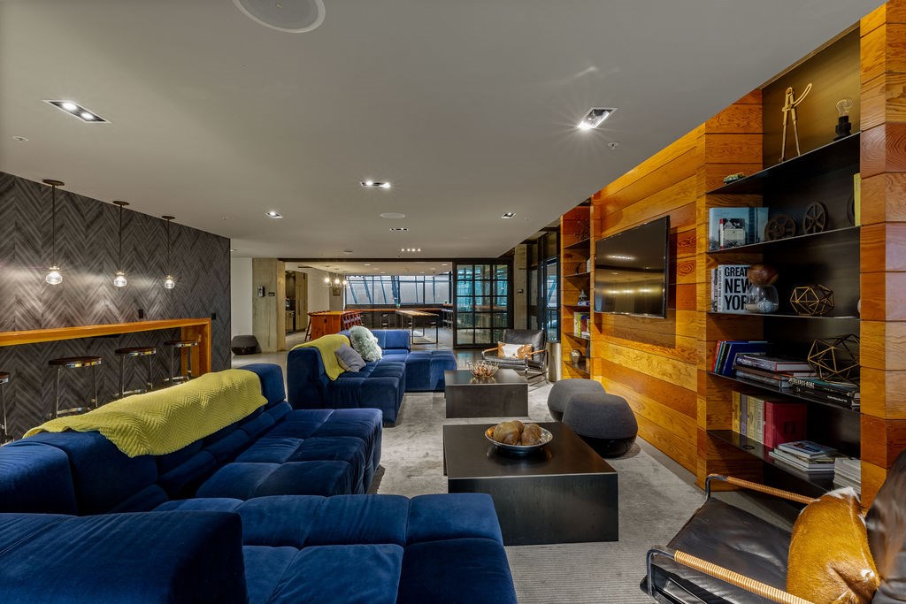 A living room with blue couches and a wooden bookshelf.