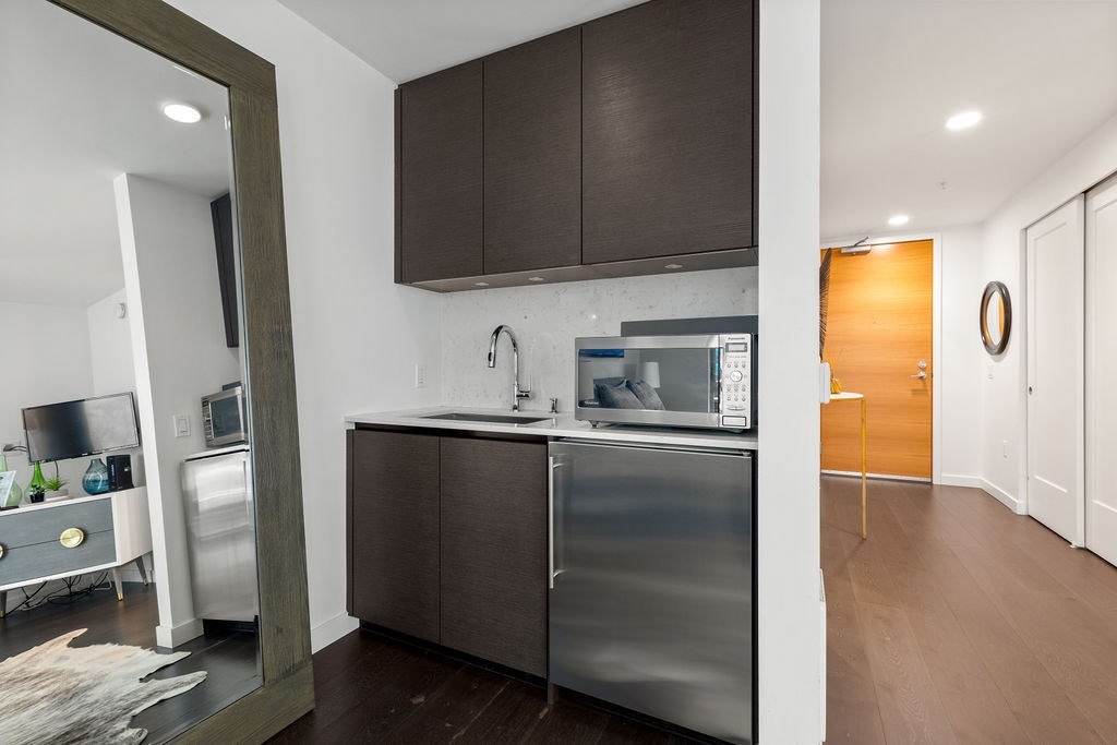 A modern kitchen with dark brown cabinets and stainless steel appliances.