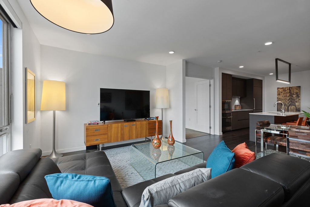 A modern living room with a black leather couch and a glass coffee table.