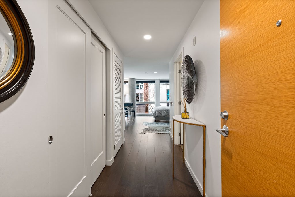 A long hallway with a fan on the wall and a brown door on the right.