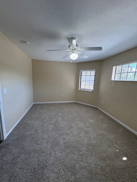 A room with a ceiling fan and carpeted floor.