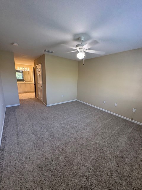 A room with a ceiling fan and carpeted floor.