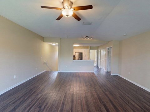 A room with a ceiling fan and wooden flooring.