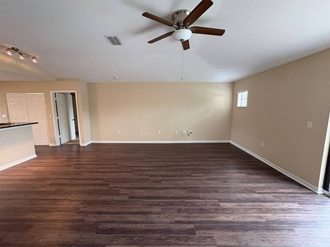 A room with a ceiling fan and wooden flooring.