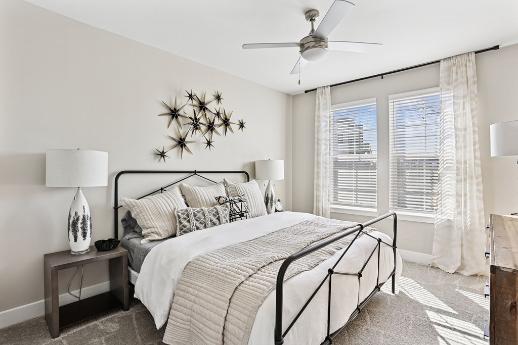 A bedroom with a large bed and a ceiling fan.
