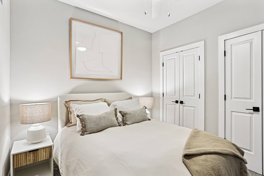 A bedroom with a bed, two lamps, and a picture on the wall.