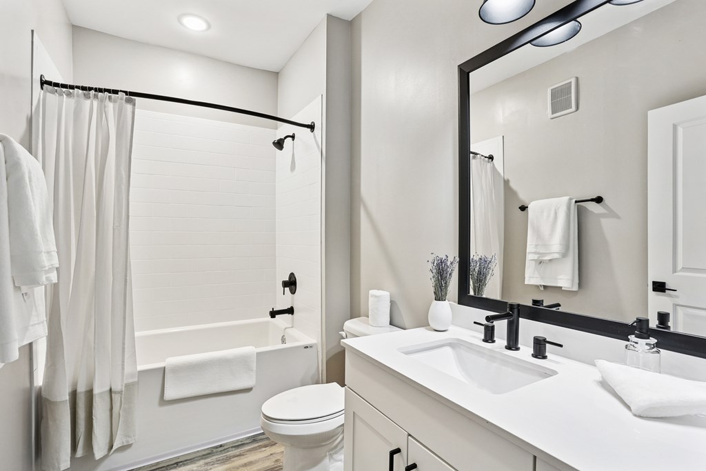 A white bathroom with a toilet, sink, and shower.