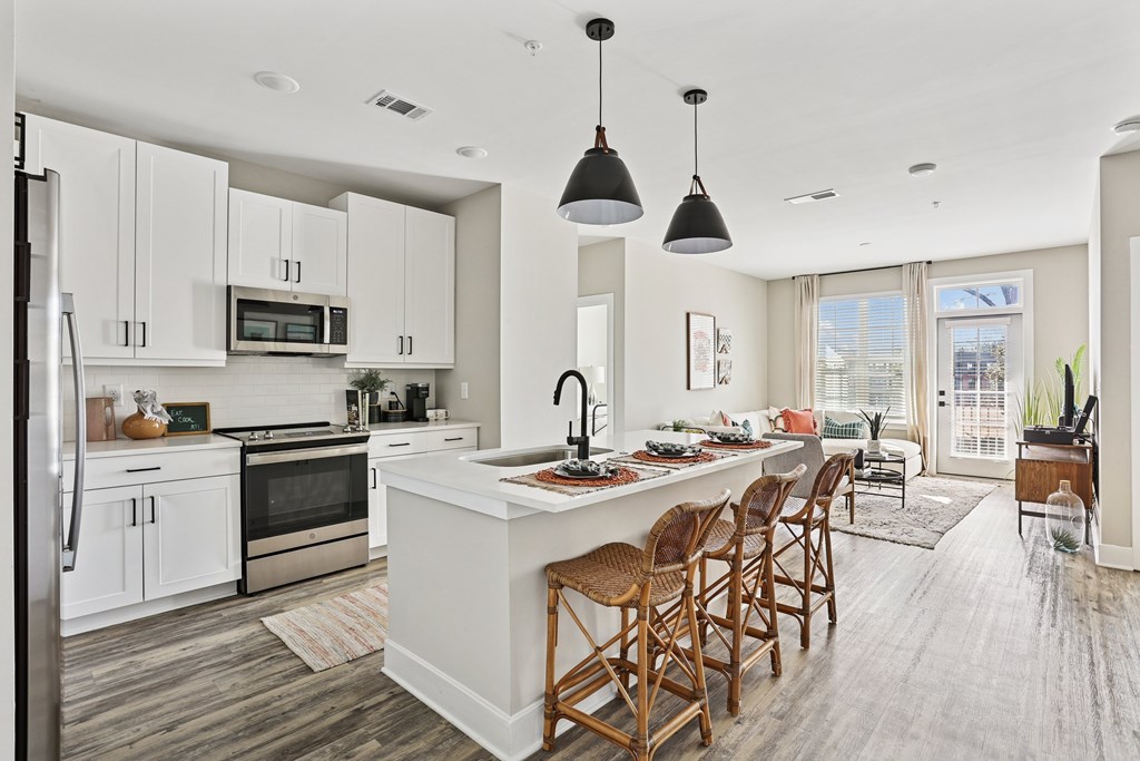 A modern kitchen with a large island and wooden chairs.
