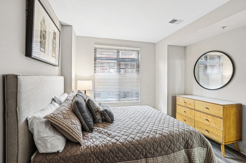 Apartment Bedroom Featuring Wood Dresser and Wall-Mounted Mirror