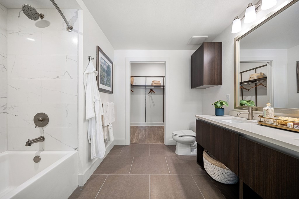 Modern bathroom with dual vanity, soaking tub, and direct walk-in closet access