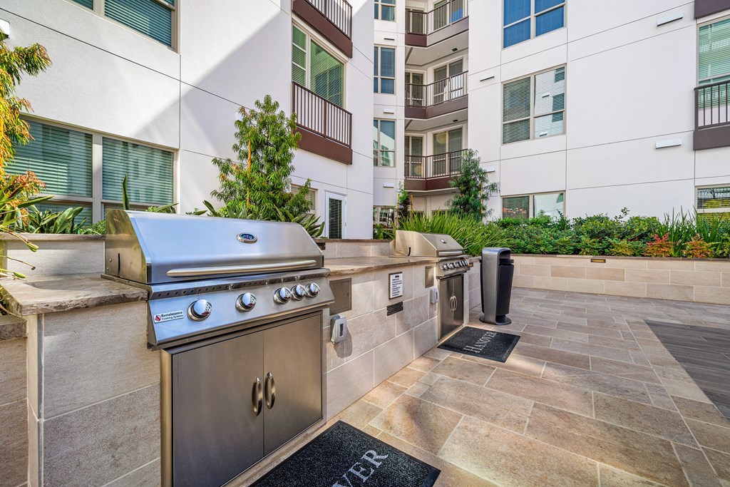Outdoor barbecue stations with stainless steel grills, set within beautifully landscaped courtyards