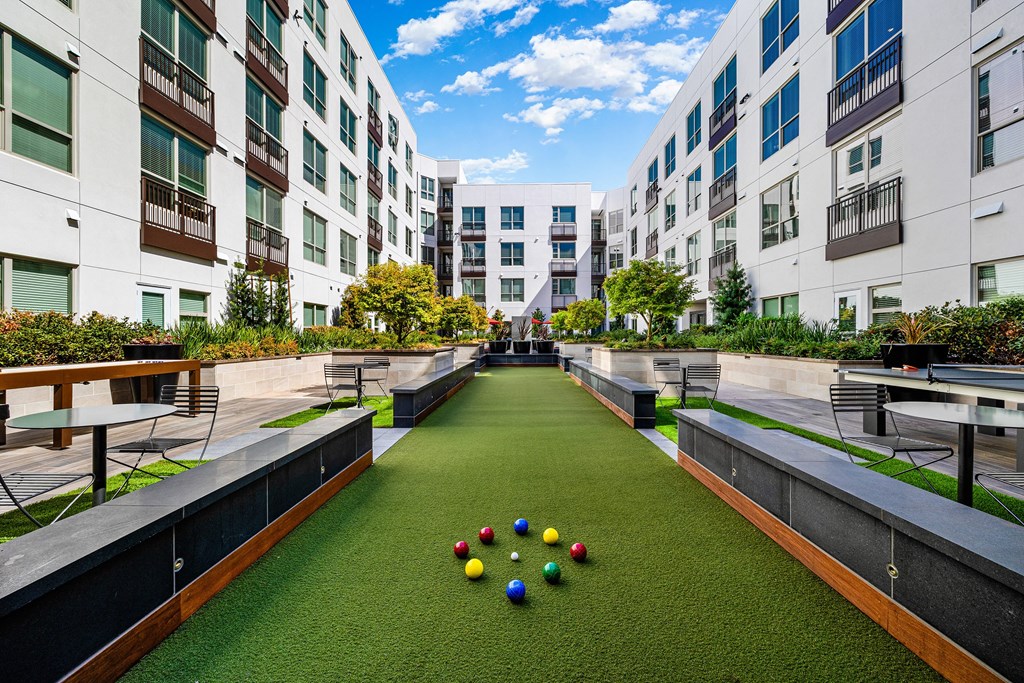 Bocce ball court surrounded by lush greenery and modern architecture, creating a vibrant community setting