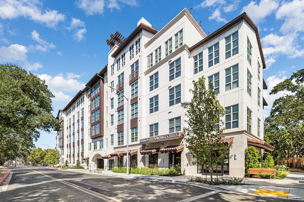Exterior view of luxury apartment community with modern design and tree-lined sidewalks