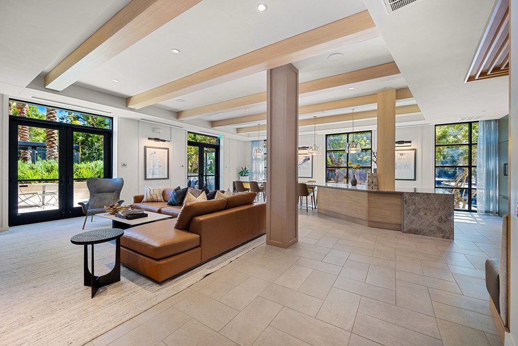 Stylish clubroom lounge with designer seating, wood accents, and walls of windows for gathering and relaxing