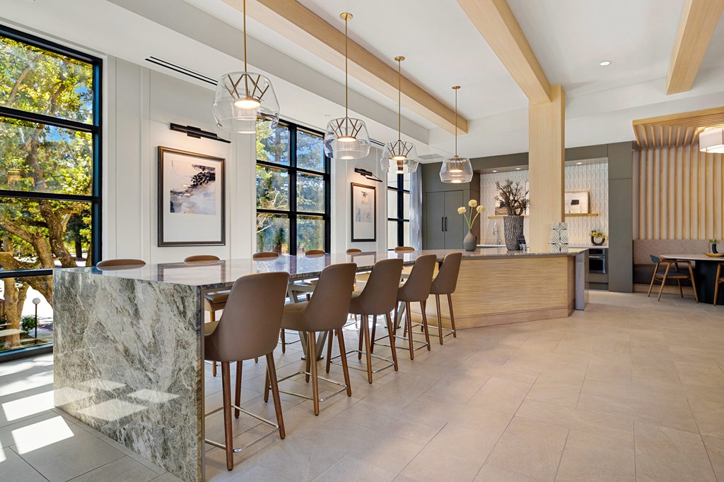Sunlit dining area with oversized stone table and striking pendant lights, perfect for hosting gatherings