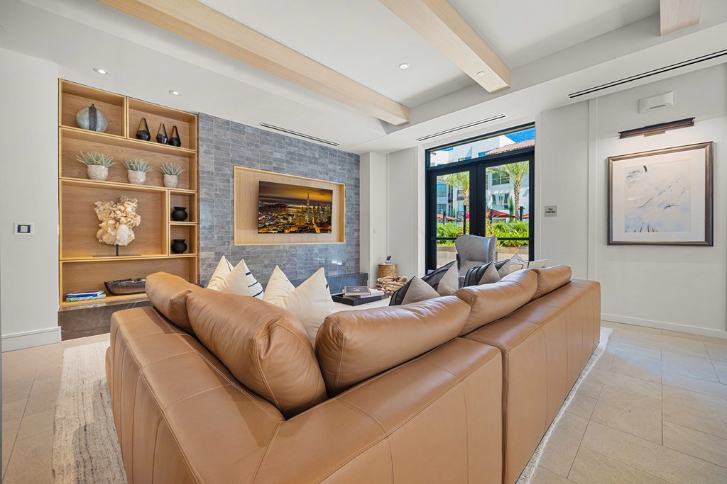 Elegant clubroom lounge featuring a leather sectional, custom shelving, and large-screen TV for movie nights