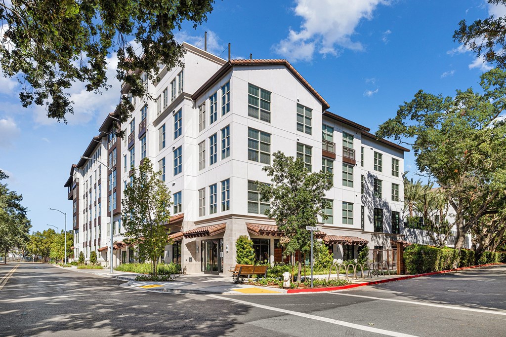A large white building with a red awning sits on a street corner.