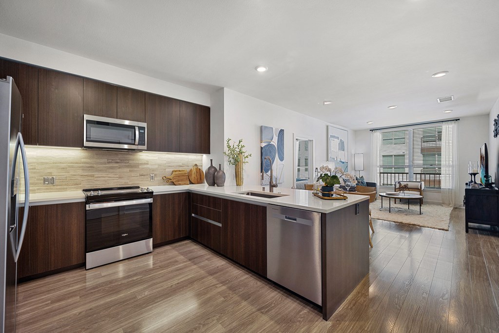 Sleek open kitchen with quartz counters and ample cabinetry that flows into a bright living area