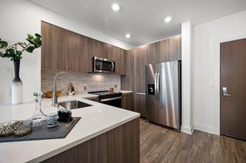 Modern kitchen with sleek wood cabinetry, quartz counters, and stainless steel appliances