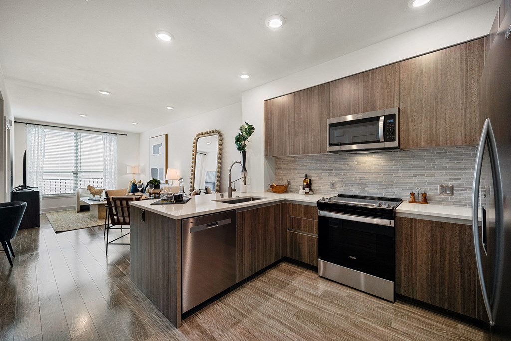 Sleek open kitchen with quartz counters and ample cabinetry that flows into a bright living area