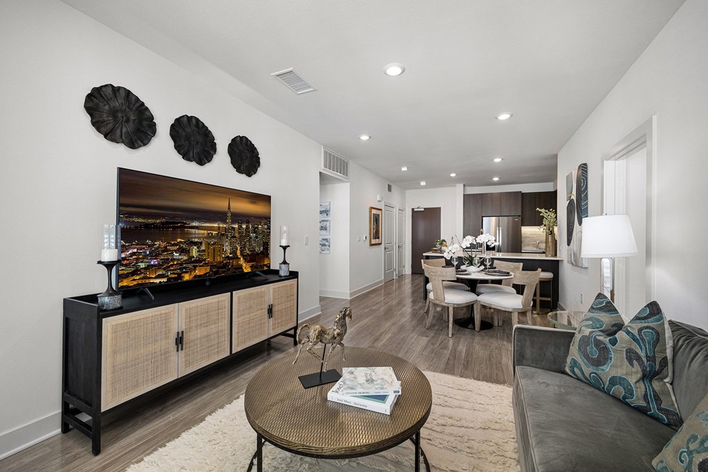 Stylish living space with soft textures, a sleek media console, and wide windows for abundant light