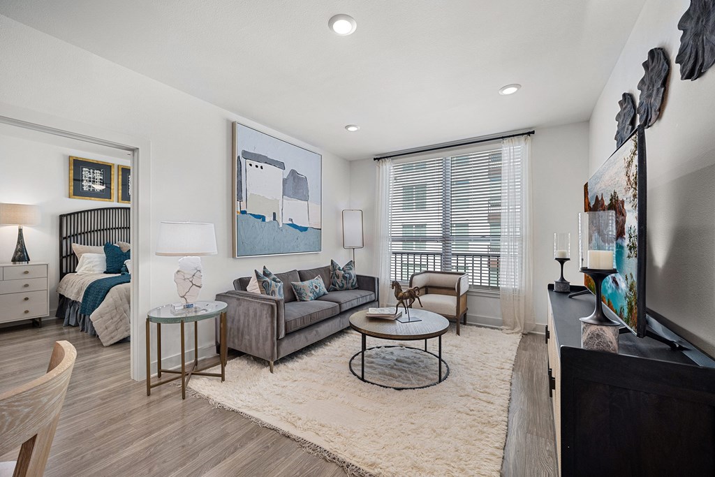 Welcoming living room with a plush sofa, contemporary artwork, and natural light streaming through large windows