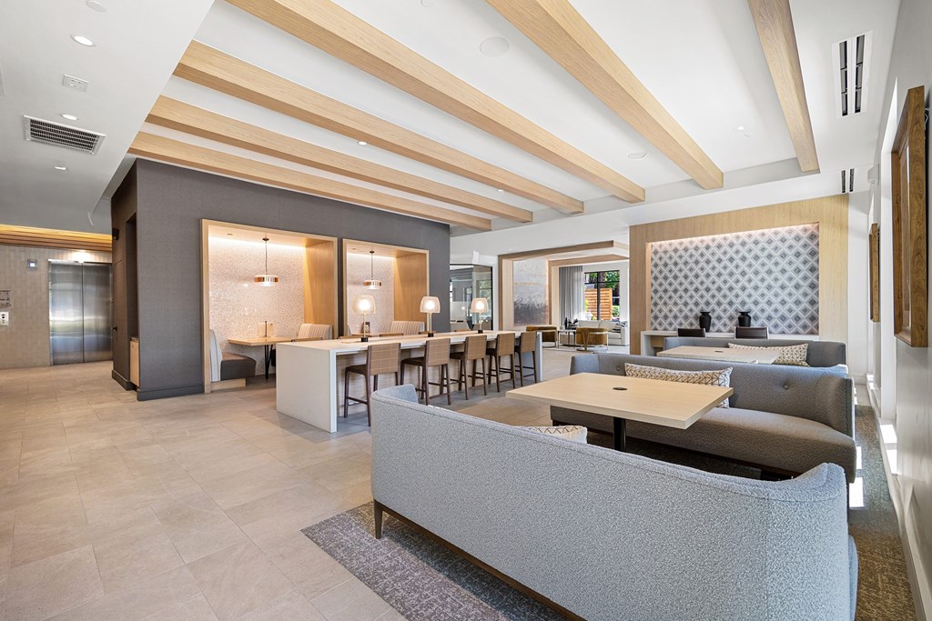 Resident lounge with flexible seating, work tables, and a warm inviting atmosphere