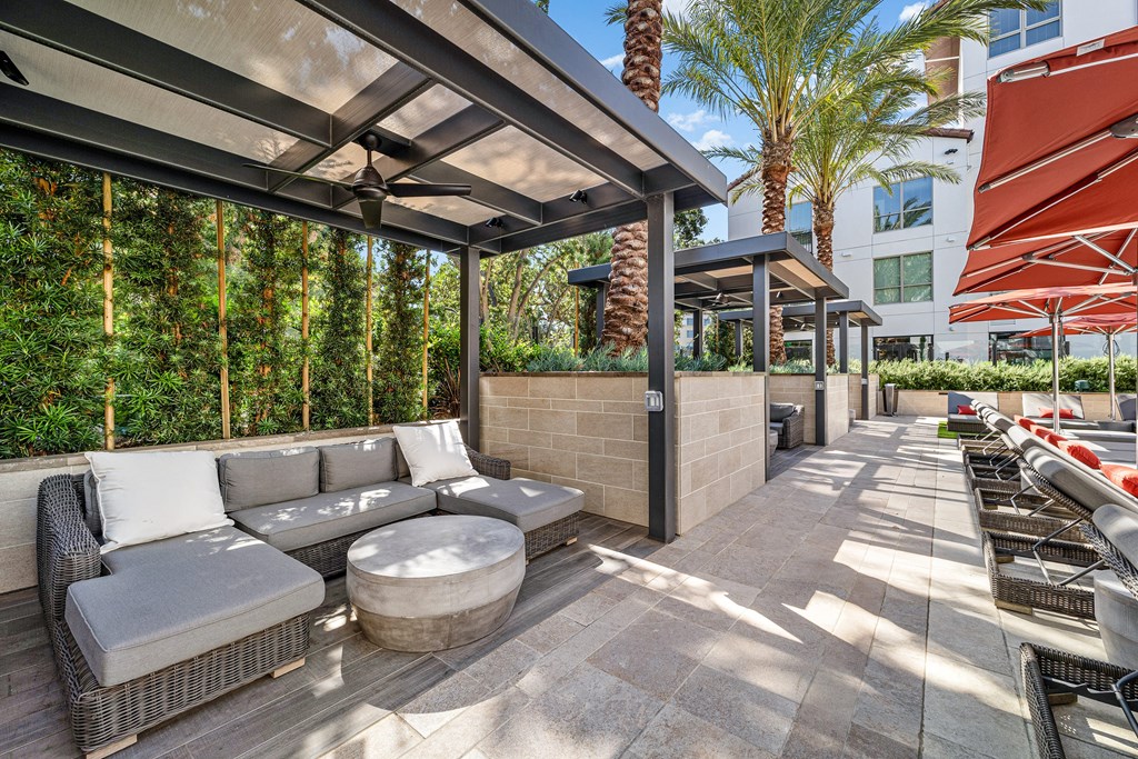 Shaded cabana seating with modern wicker furniture and ceiling fans for breezy afternoons by the pool
