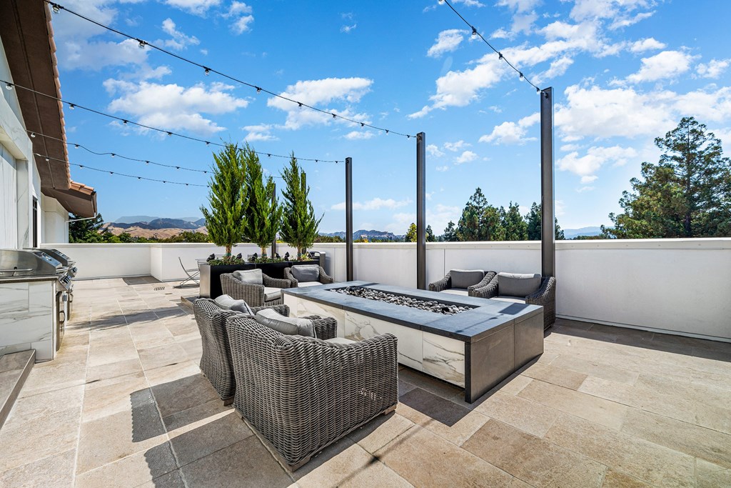 Rooftop terrace with lounge seating, outdoor firepit, and views of rolling hills