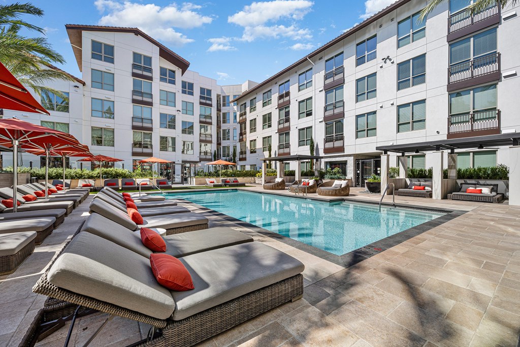 Resort-inspired pool deck with cushioned loungers, red umbrellas, and sparkling water perfect for relaxing weekends