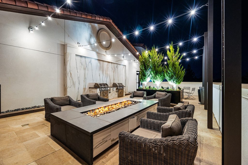 Rooftop terrace with fire pit lounge, string lights, and plush seating designed for cozy evenings
