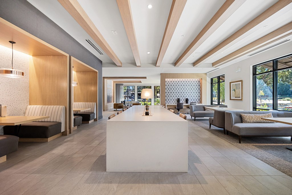 Open lounge with long communal table, semi-private booths, and floor-to-ceiling windows