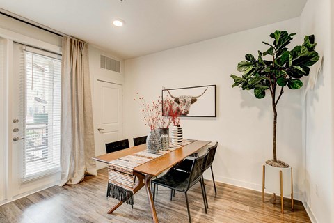 Dining area with a four-seat table, wood-style flooring, and glass patio door.