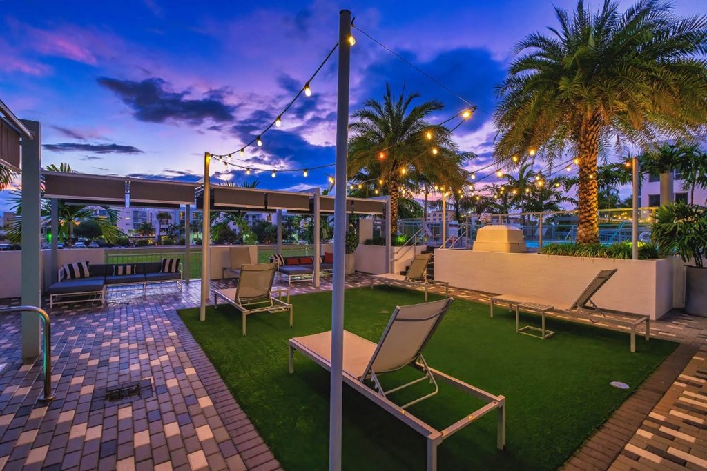 a rooftop patio with chairs and grass and palm trees