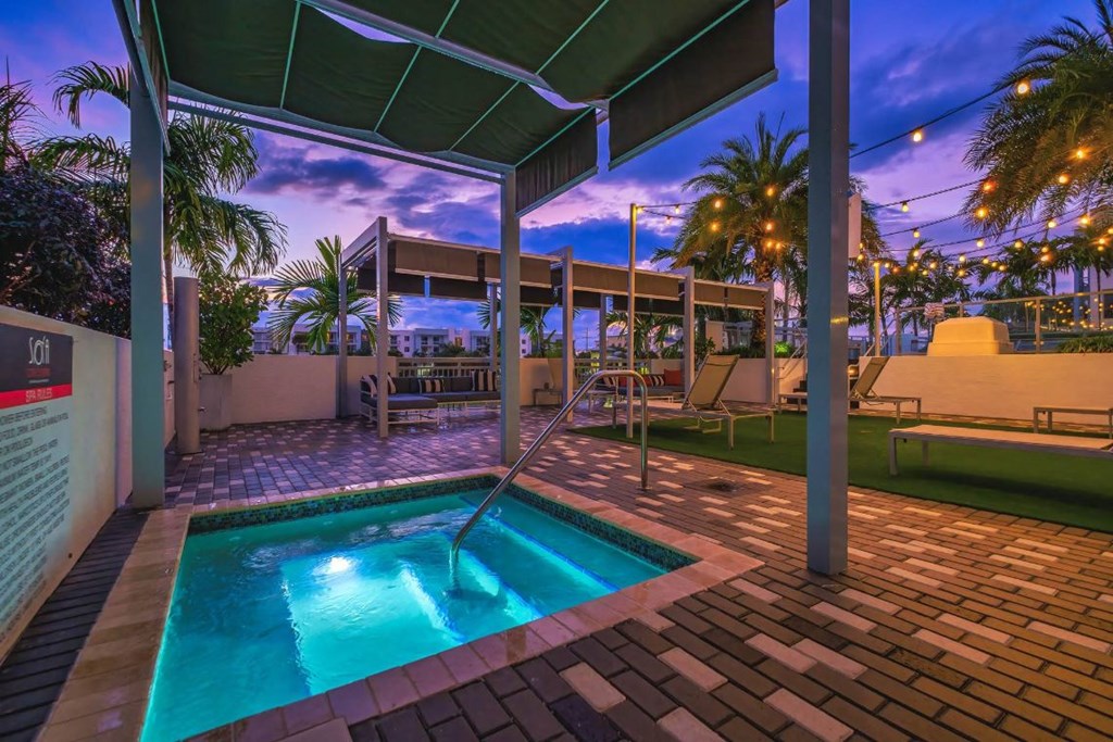 the pool is under a covered patio with palm trees