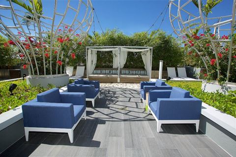 a seating area with blue chairs and a swing set in a garden