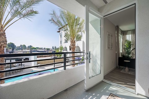 Private apartment balcony with a metal railing and views of the pool courtyard.